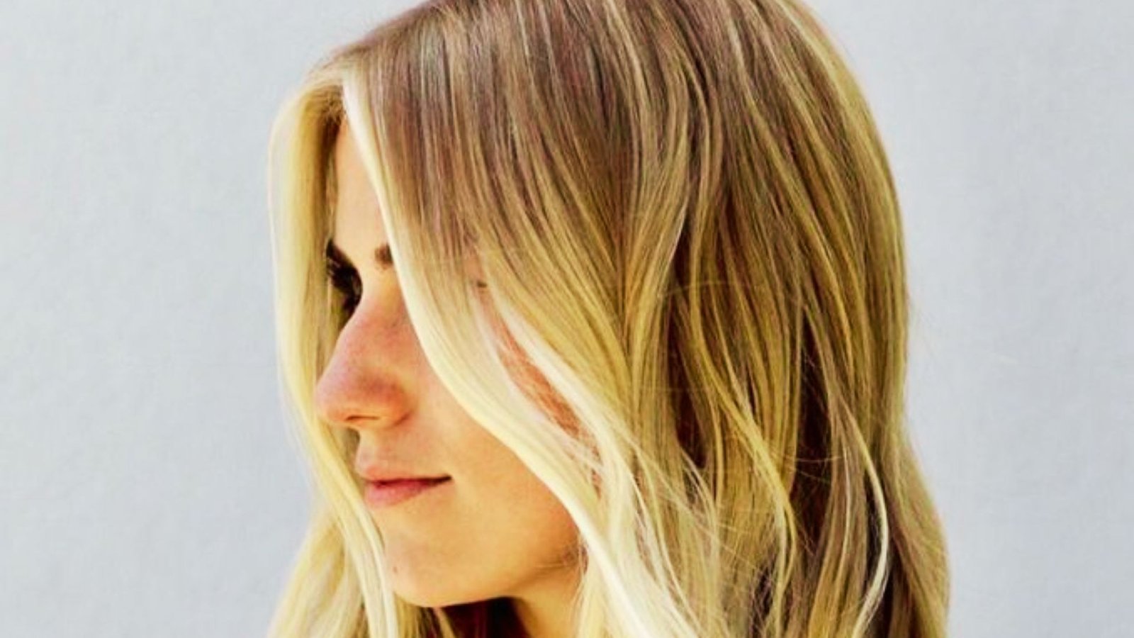  A woman with long hair styled in layers, featuring curtain bangs and highlighted money pieces.
