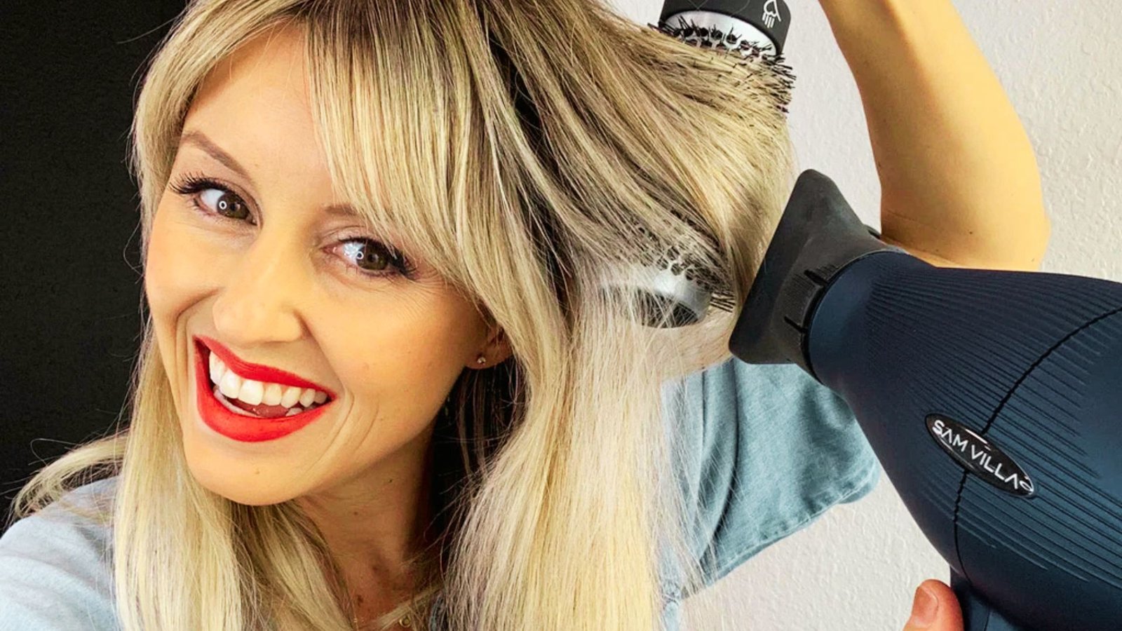 A woman blow dries her hair upside down using a blow dryer on the cool setting for added volume.
