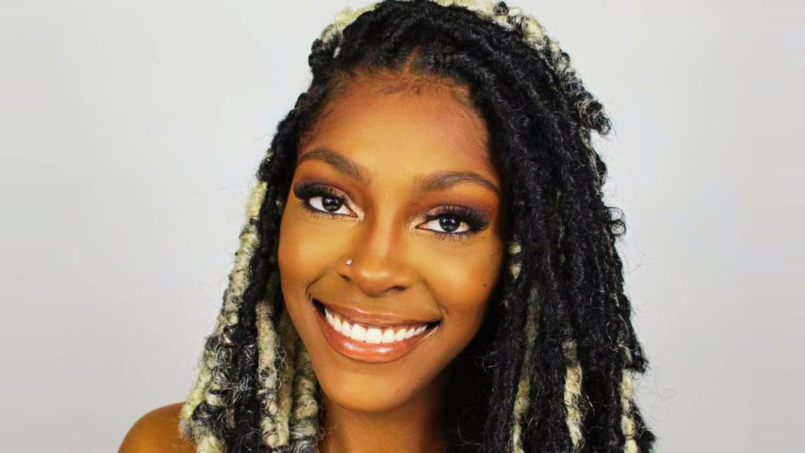 A beautiful woman with short dreadlocks styled nicely for a glam party, showcasing faux locs ideas.