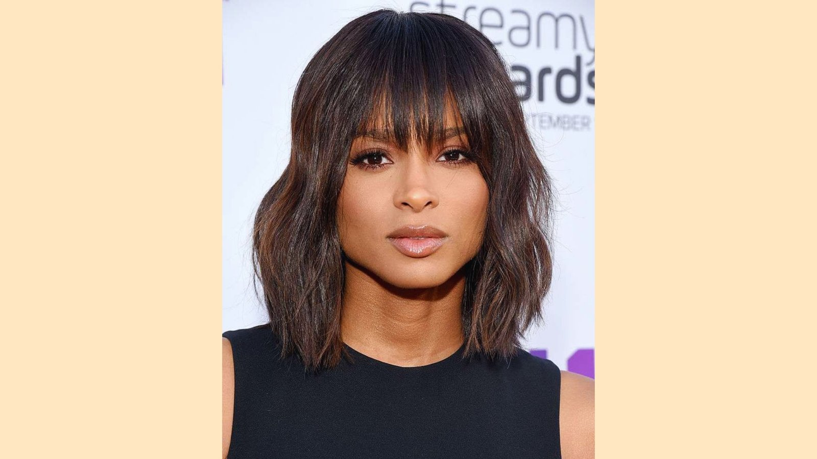 Wispy curtain bangs on wavy shoulder-length bob with dimensional brunette highlights and tousled texture