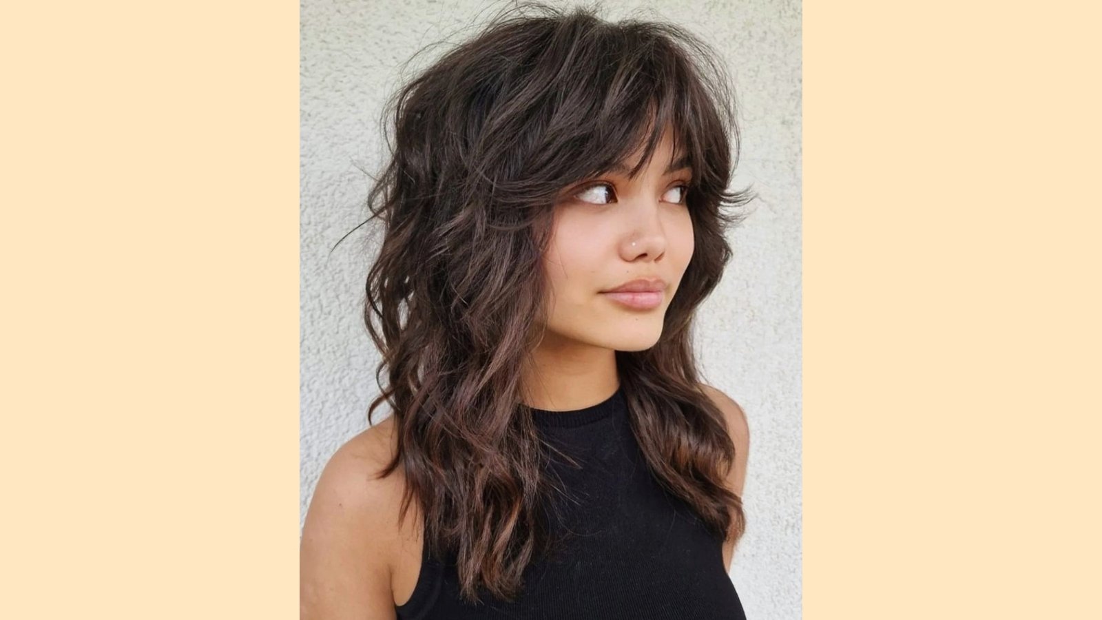 Long wavy layered shag with wispy curtain bangs and soft face-framing texture on dark brown hair