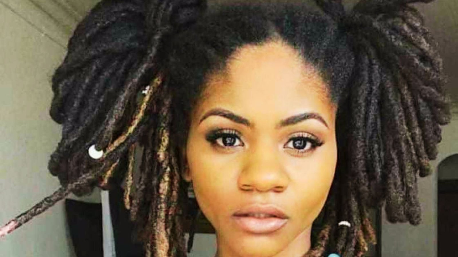 A woman with a low knot wicks hairstyle looking towards the camera.