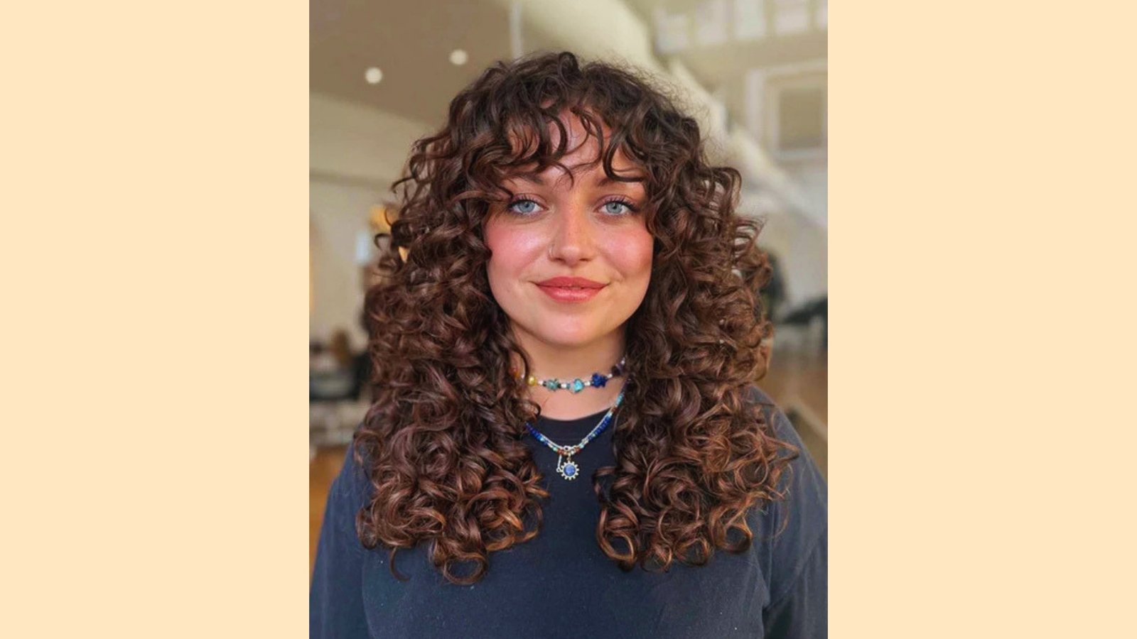 Long voluminous curly brown hair with wispy curly curtain bangs and defined natural texture