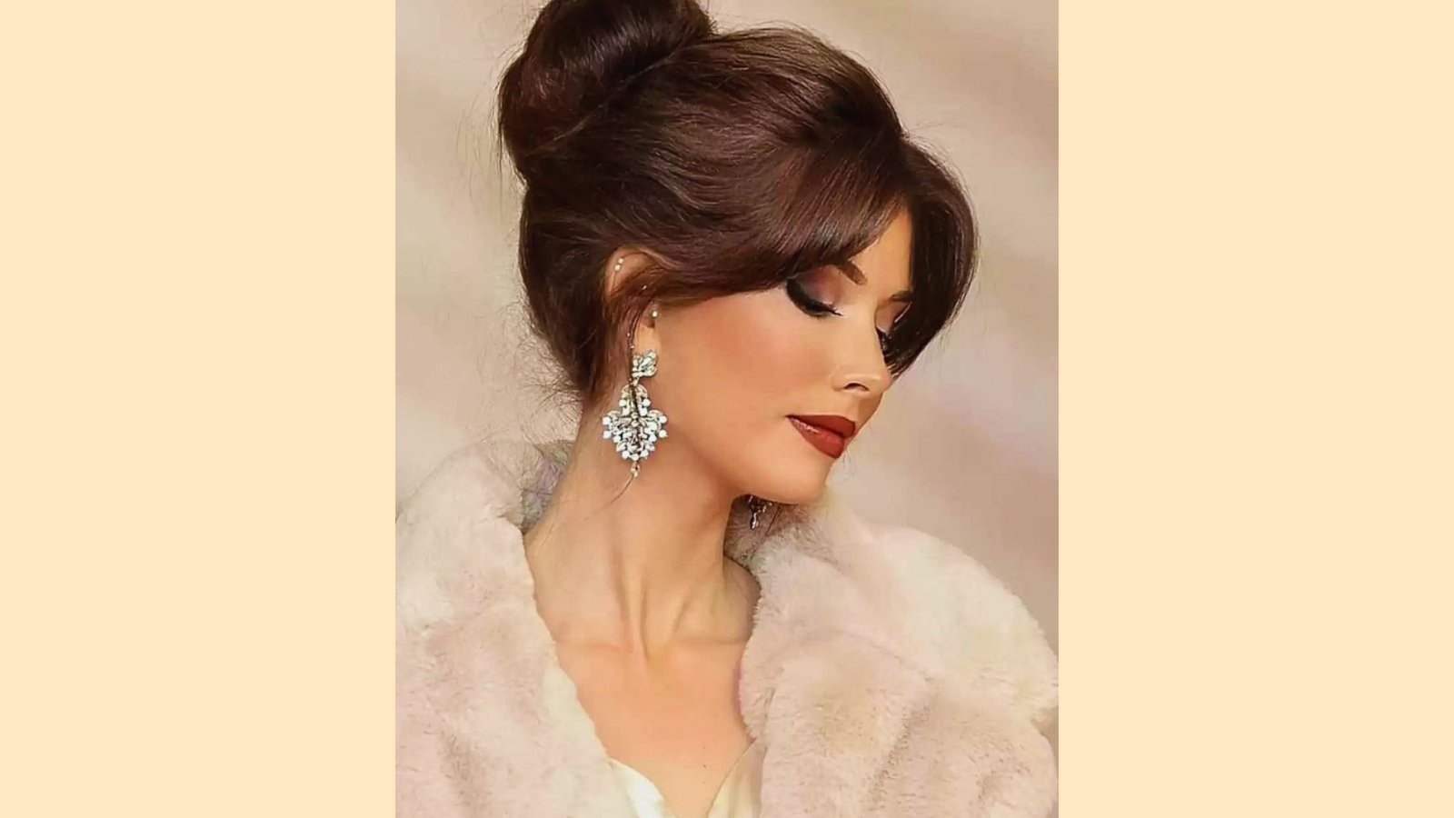 High bun updo with wispy curtain bangs and polished finish on dark brown hair