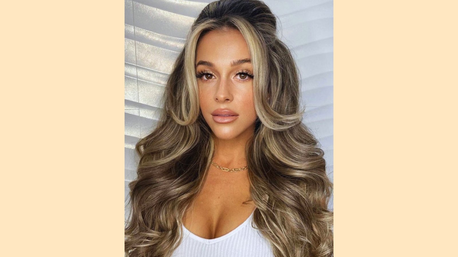 Long voluminous wavy bronde hair with bold wispy curtain bangs and chunky blonde face-framing highlights