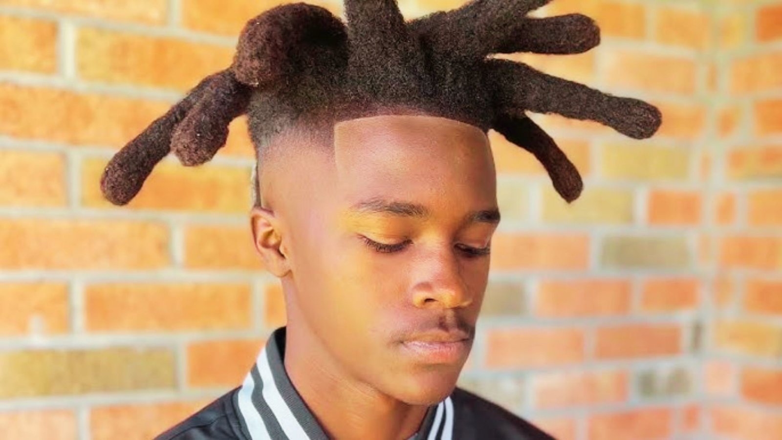 A young man with dreadlocks, featuring a 6 Wicks hairstyle,