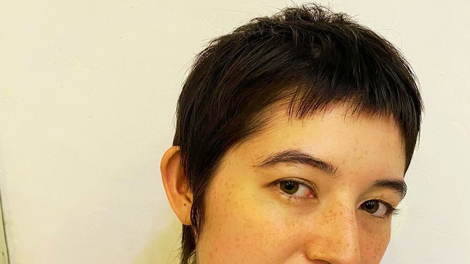 A woman with a short pixie cut, featuring a long top and round face, showcasing her stylish hairstyle.