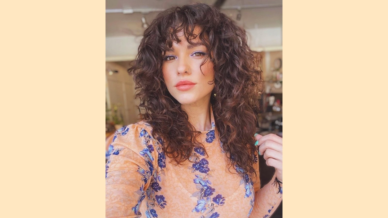 Long voluminous curly brown hair with wispy curly curtain bangs and soft face-framing layers