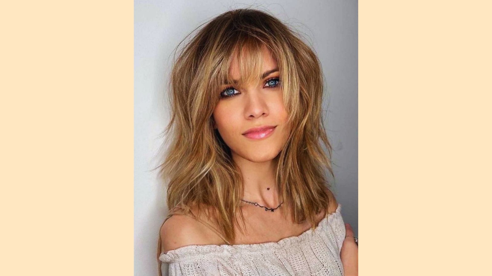 Medium length blonde layered haircut with wispy curtain bangs and choppy piecey texture