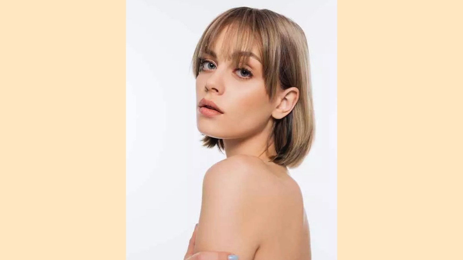 Short straight bob with wispy see-through curtain bangs on light brown hair