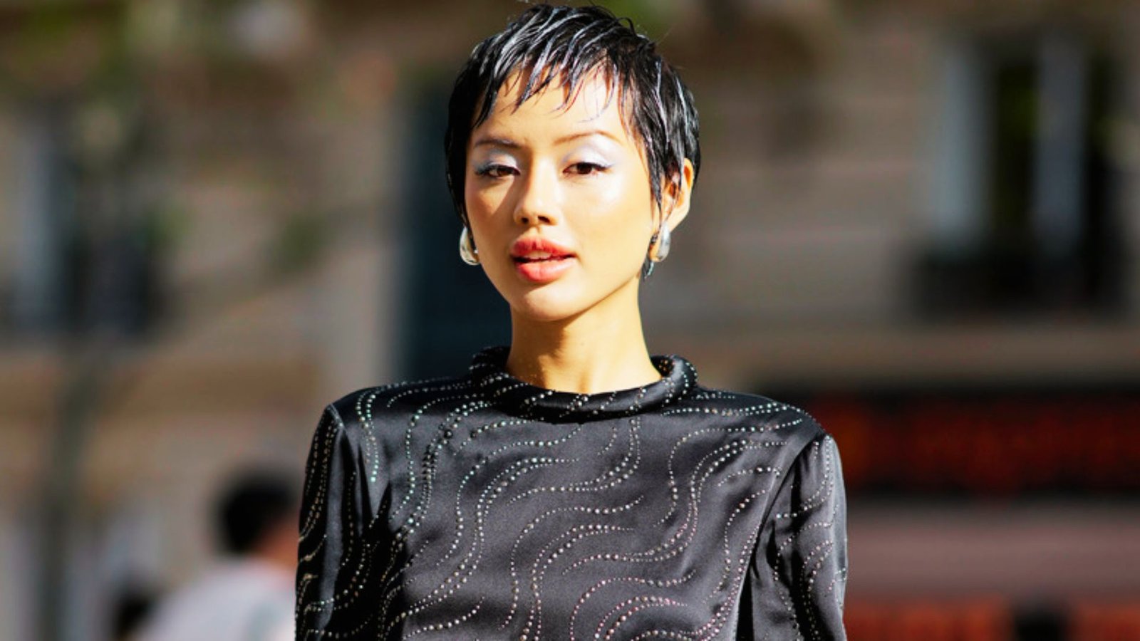 A woman with a punk-influenced messy pixie cut wearing a black dress, exuding a bold and stylish appearance.
