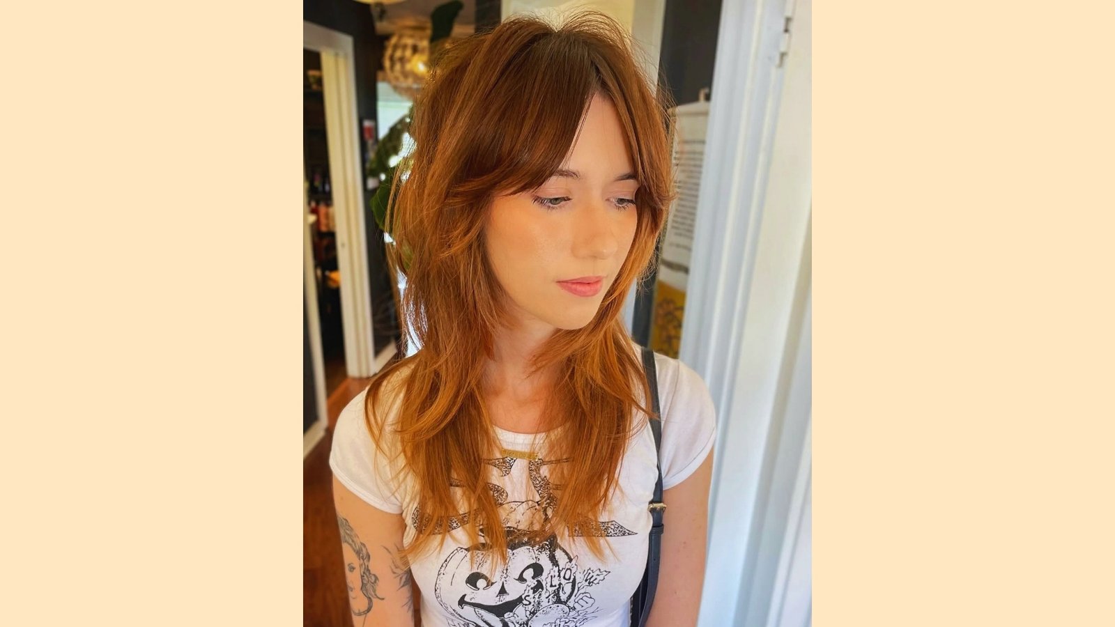 Long layered shag haircut with wispy curtain bangs and textured waves on copper auburn hair