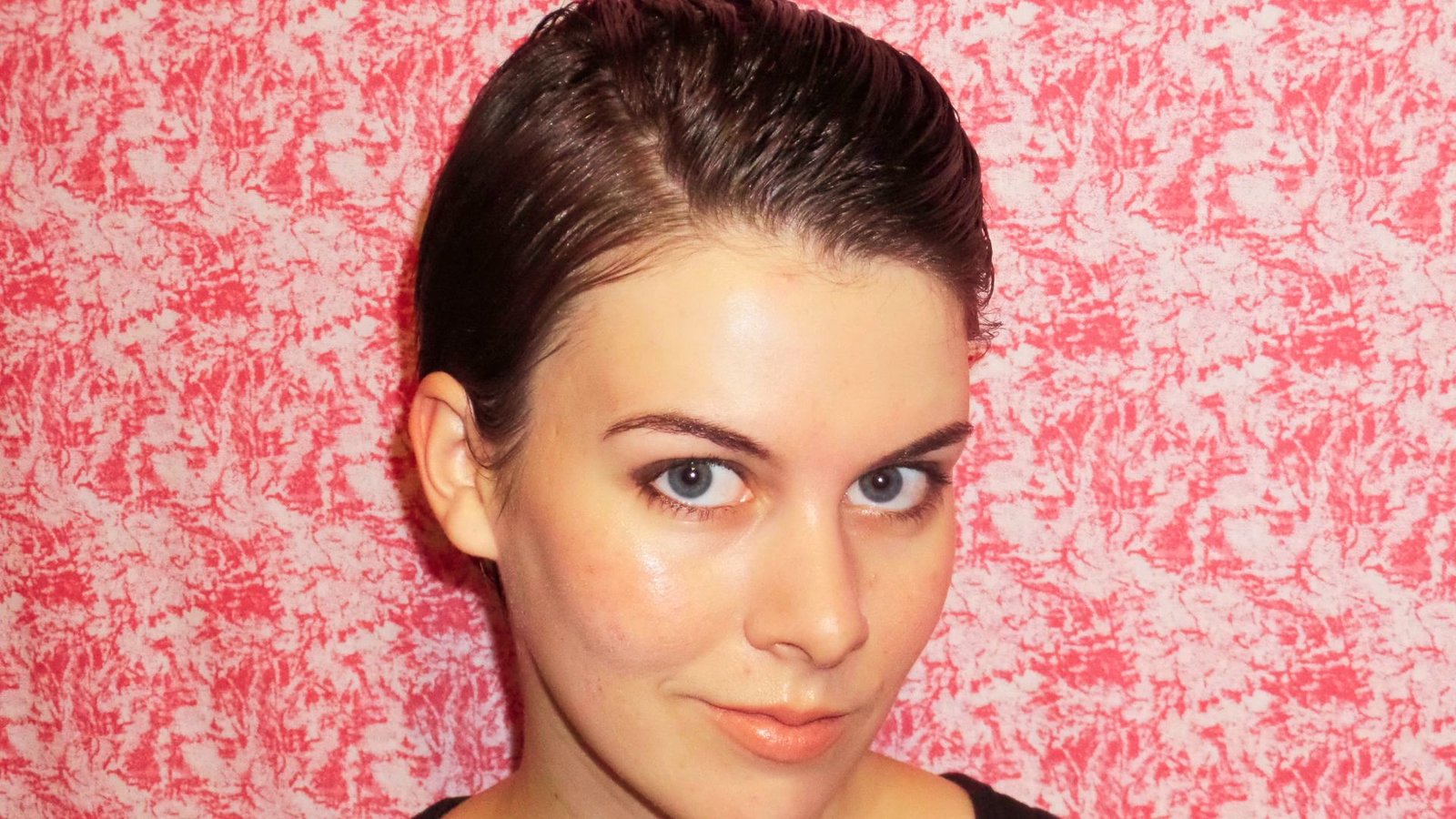A woman in a black top , featuring a slicked-back messy pixie cut, exuding confidence and style.