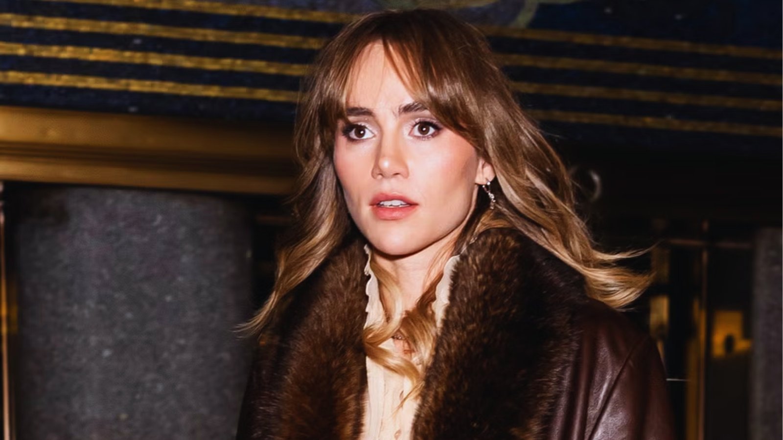 Wispy curtain bangs on medium-long wavy brunette hair with caramel highlights and face-framing layers