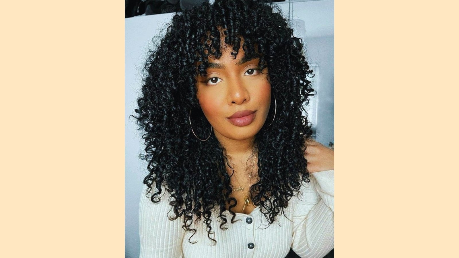 Medium length layered shag haircut with wispy curly curtain bangs on tight black coils and rounded shape