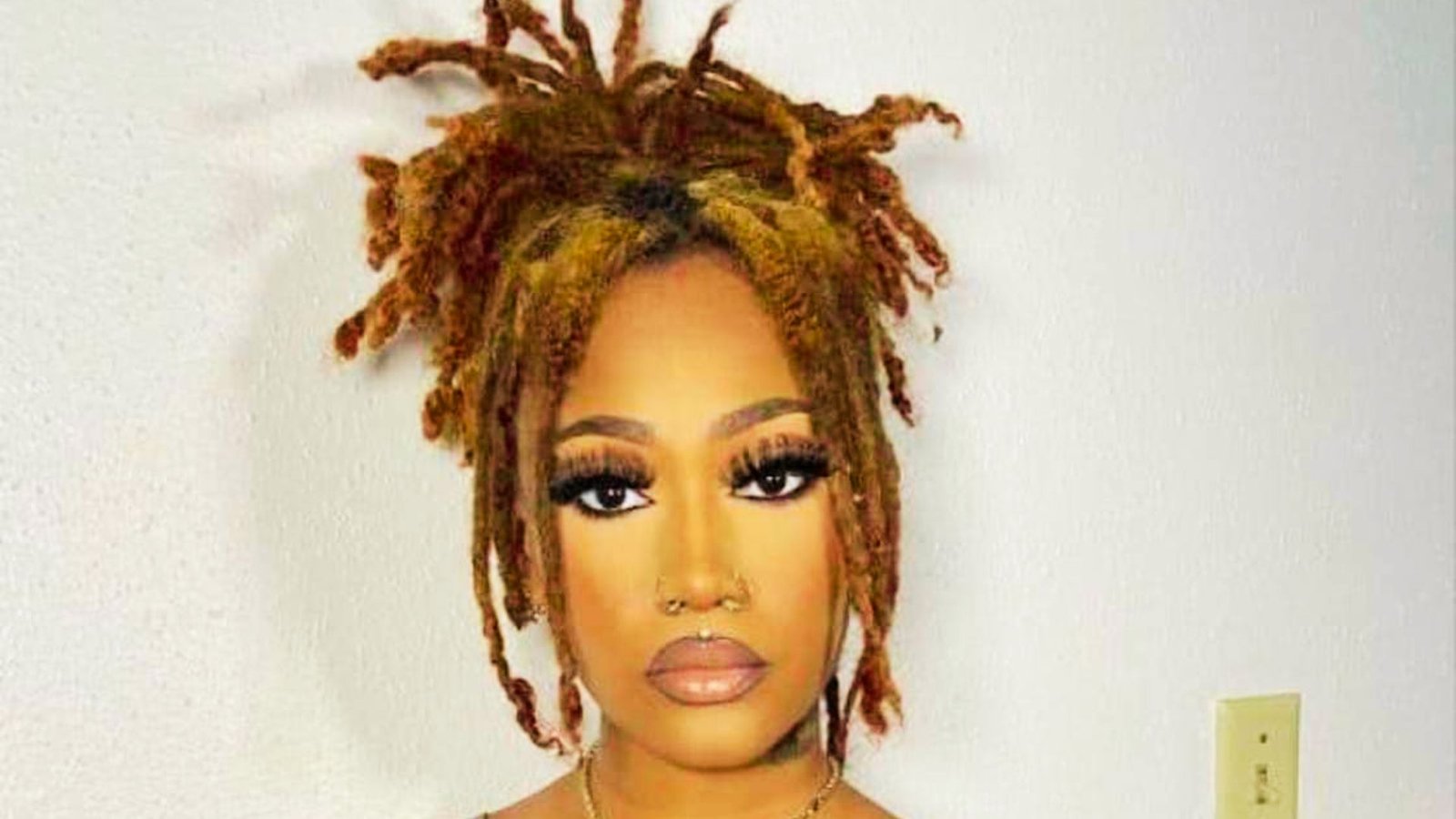 A woman with dreadlocks wearing a stylish necklace, showcasing a bold hairstyle idea for a fresh look.