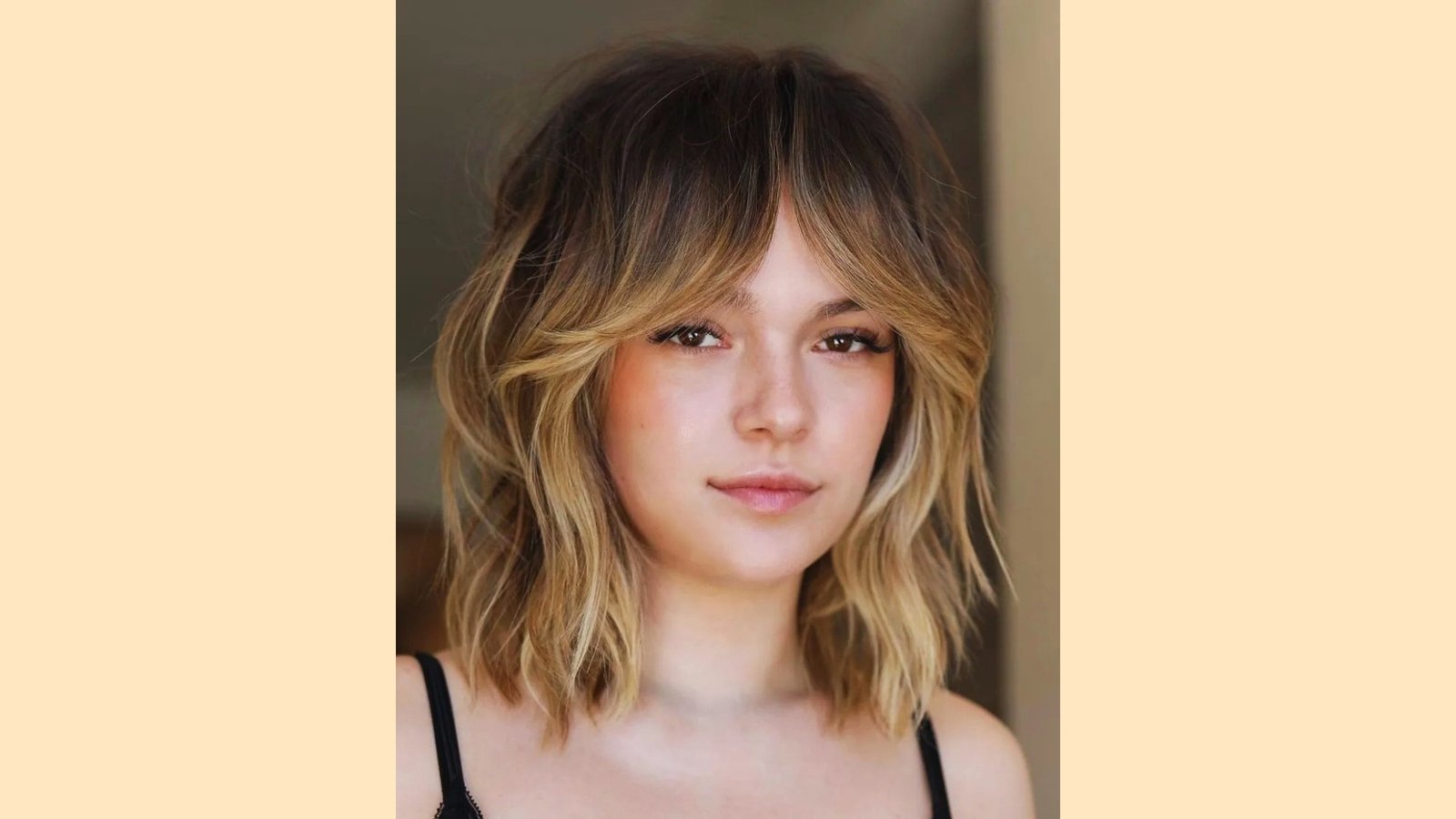 Shoulder-length wavy blonde hair with wispy curtain bangs and textured layers