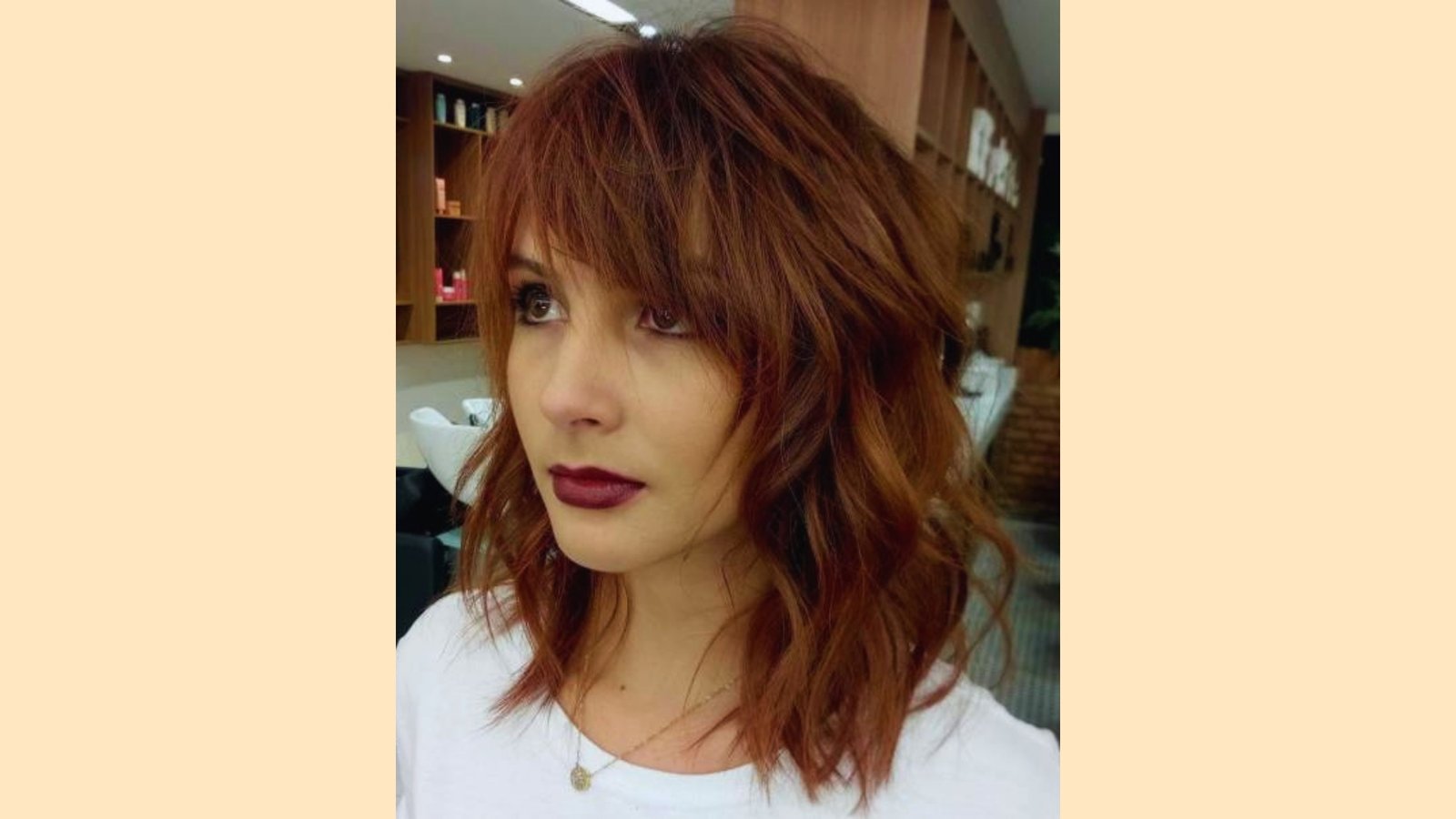Medium length wavy auburn shag with wispy curtain bangs and choppy textured layers