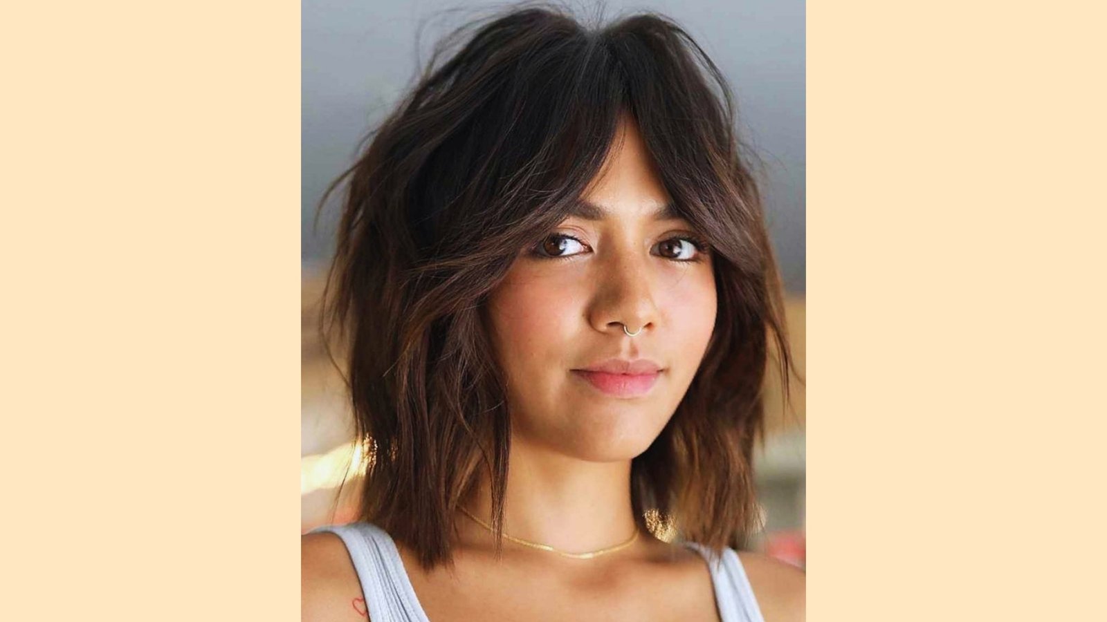 Shoulder-length wavy dark brown shag with wispy curtain bangs and textured layers