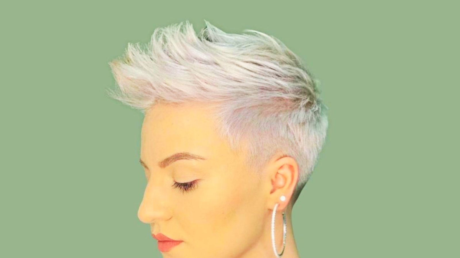 A woman with short, spiky white hair and earrings, showcasing an edgy pixie cut.