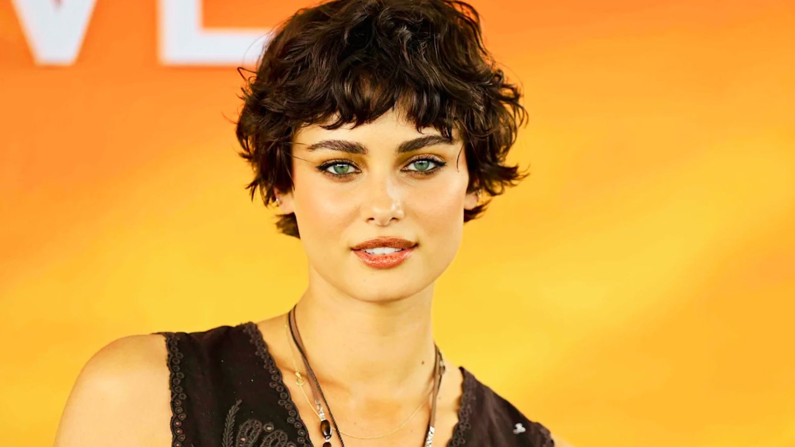 A woman with a voluminous pixie cut and short hair, wearing a black top.