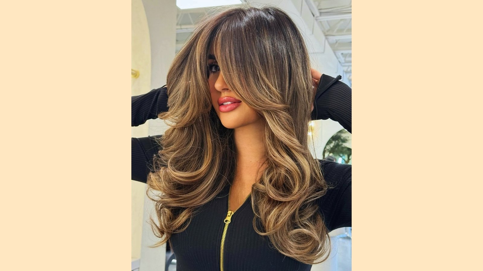 Long wavy hairstyle with wispy curtain bangs and caramel balayage highlights on brunette hair