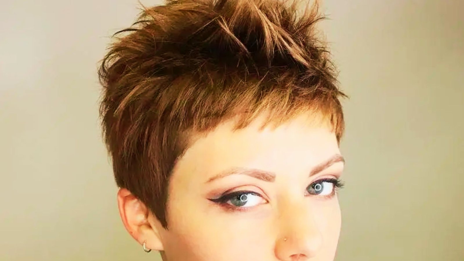 A woman with a spiked crown pixie cut and a blue shirt, showcasing her short hair.