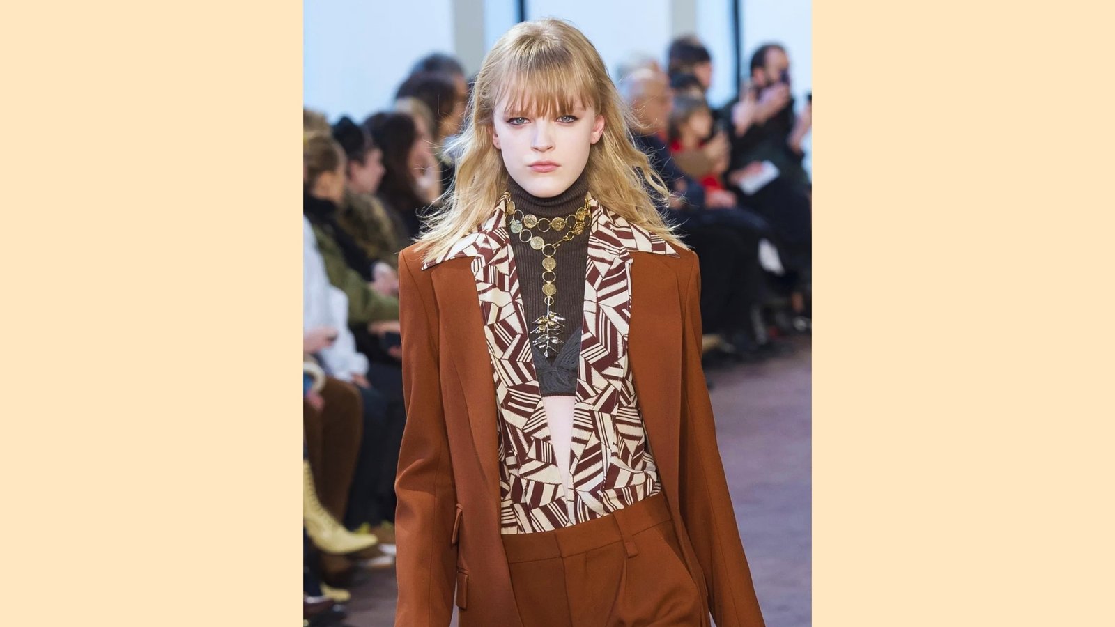 Runway model with long wavy blonde hair and wispy see-through blunt bangs styled with center-parted movement